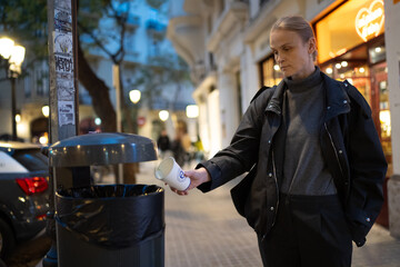 Woman disposing of cup in city trash