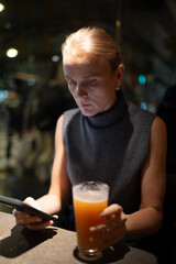 Woman in turtleneck holding juice at night