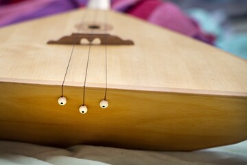 Plastic round buttons securing metal strings to the soundboard of a traditional wooden balalaika