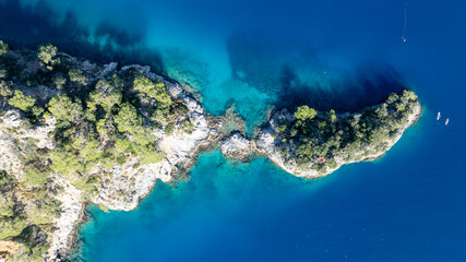 Top-down aerial view of dramatic cliffs meeting bright turquoise summer bays