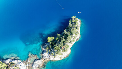 Top-down aerial view of dramatic cliffs meeting bright turquoise summer bays