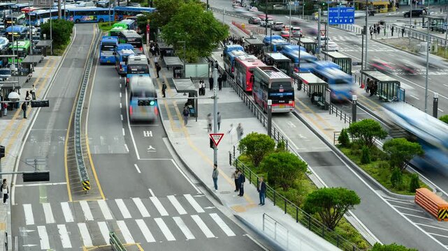Time lapse of the Seoul Station area, featuring multiple bus lanes, bus stops with people waiting, traffic on busy roads. Captures the well-organized public transport system.