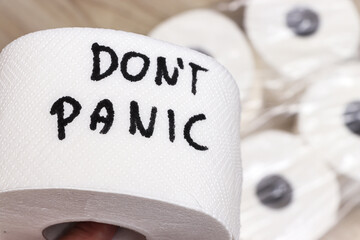 A view of a roll of toilet paper with the handwritten message Dont Panic. It is surrounded by additional rolls, conveying a sense of urgency and humor during uncertain times.