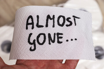 A hand holds a piece of paper towel with the phrase almost gone written on it, highlighting the...