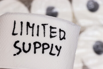 Handwritten text reading limited supply on white toilet paper roll. The image represents scarcity...