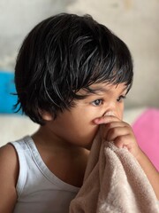 Close up portrait of a sick Asian girl holding a towel in her hand with a sad face at home
