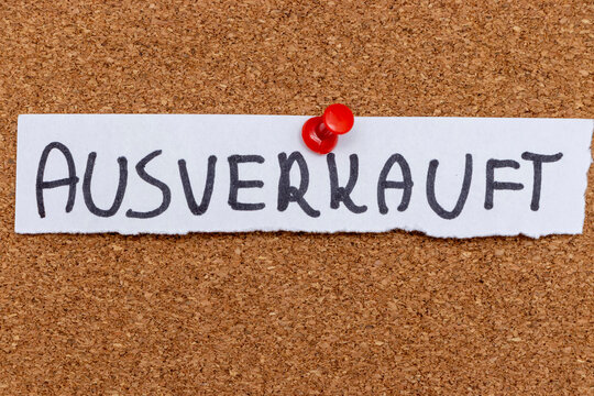 A handwritten note reading AUSVERKAUFT is pinned to a corkboard. This German term means sold out and conveys unavailability, often used in retail or event contexts.