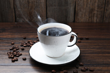 Aromatic coffee in cup and beans on wooden table, closeup