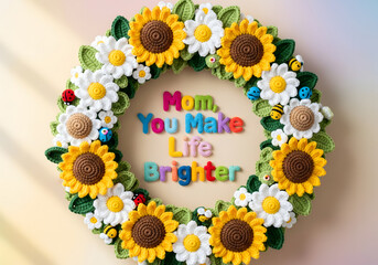 Crochet daisies and sunflowers forming a joyful wreath around “Mom, You Make Life Brighter,”
