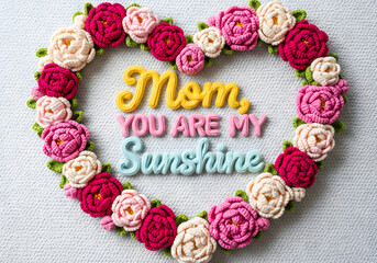 Crochet peonies forming a heart-shaped frame around “Mom, You Are My Sunshine,” with flowing 3D crochet typography, vibrant colors.