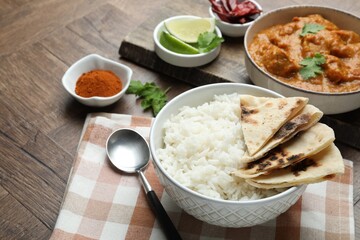 Delicious rice, lavash, chicken tikka masala and spices on wooden table, closeup