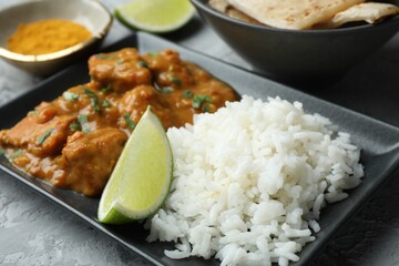 Chicken tikka masala with rice served on grey textured table, closeup