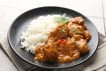 Chicken tikka masala with rice served on light tiled table, closeup