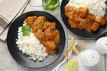 Chicken tikka masala with rice served on light tiled table, flat lay