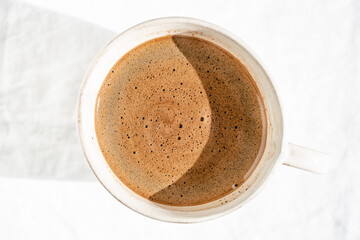 Cup of hot coffee in sunlight.