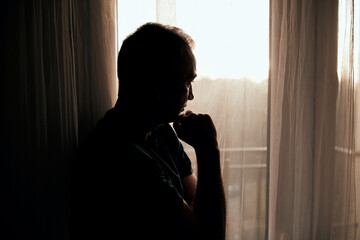 Silhouette of depressed, sad and lonely man in the apartment.
