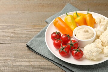Different fresh vegetables and sauce on wooden table, closeup. Space for text