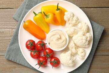 Different fresh vegetables and sauce on wooden table, top view