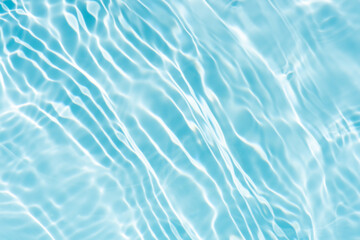 Blue water with ripples on the surface. Defocus blurred transparent blue colored clear calm water surface texture with splashes and bubbles. Water waves with shining pattern texture background.