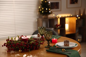 Christmas table setting with plates, glasses and burning candles in festive decorated room