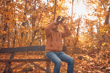Amateur birdwatcher observing birds and other animals in nature with binoculars.
