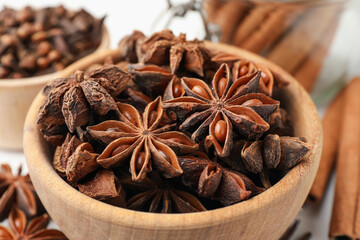 Mulled wine spices. Anise stars in wooden bowl and cinnamon sticks on white table, closeup