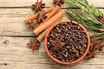 Different spices in bowl and fresh rosemary for mulled wine on wooden table, flat lay. Space for text