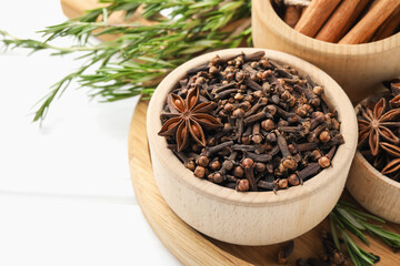 Different spices in bowls and fresh rosemary for mulled wine on white table, closeup. Space for text