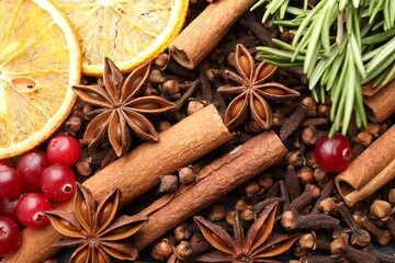 Different spices, fresh rosemary, cranberries and dry orange slices for mulled wine as background, top view