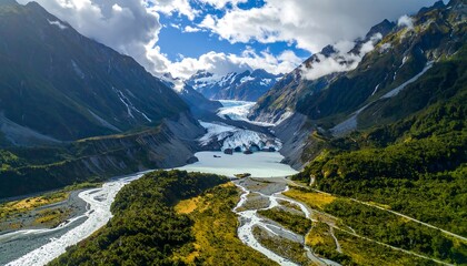 Aerial view of a glacial lake nestled between majestic mountains under a partly cloudy sky. Glacial melt flows