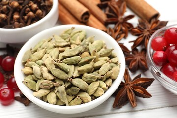 Different spices and cranberries for mulled wine on white wooden table, closeup