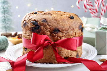 Tasty Christmas panettone cake decorated with red ribbon on table, closeup