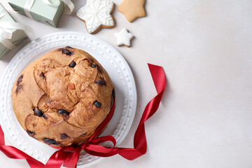 Tasty Christmas panettone cake, gingerbread cookies and gifts on beige table, flat lay. Space for text