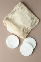 Clean cotton pads and bag on beige background, flat lay