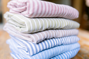 Soft pastel striped shirts neatly folded for closet organization, showcasing fresh laundry and calming colors for a peaceful home aesthetic, perfect for spring cleaning inspiration