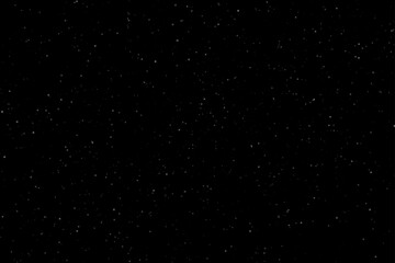 Soft white dust particles of various sizes and transparencies scattered on a solid black background. Minimalistic texture without flares or highlights, ideal for abstract and festive designs.