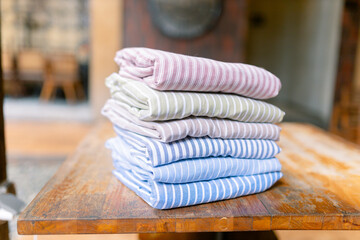 Freshly laundered striped towels neatly stacked on rustic wood table bring a touch of simple elegance to your home decor, evoking feelings of cleanliness and comfort