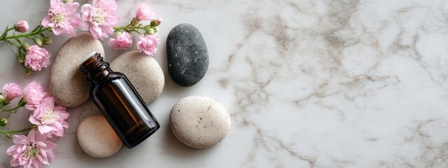 A calming arrangement of smooth massage stones, an amber oil bottle, and pink flowers on a marble surface