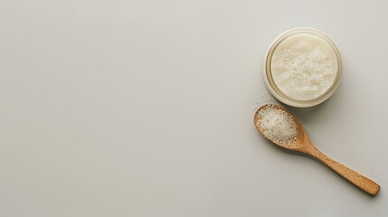 Naklejka na ściany i meble Top-down view of sea salt in a jar and a wooden spoon on a white background
