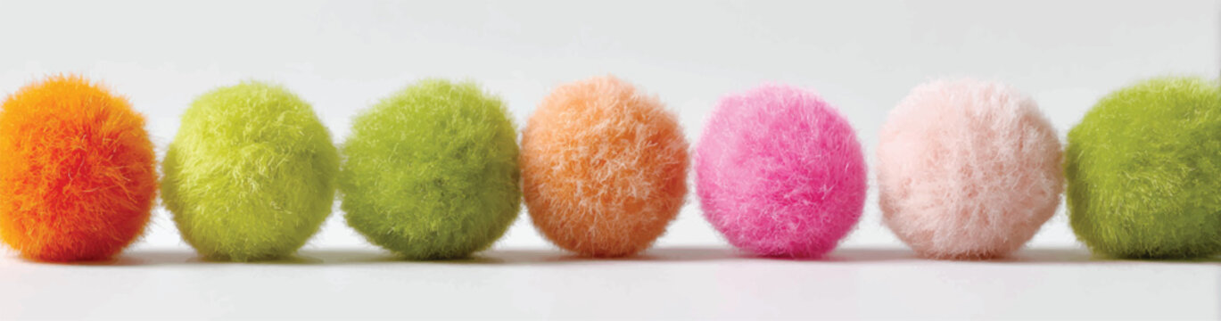 Colorful Pom Poms in a Row on White Background Close Up