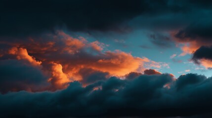 Obraz premium Cinematic view of a moody sky featuring dark heavy storm clouds illuminated by vibrant orange sunlight at dusk. Atmospheric nature background.