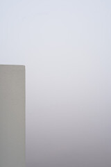 Fog and smog in the city. A fragment of a building wall against a backdrop of thick fog or smog. Vertical photo. Copy space. Minimalistic photo with negative space.