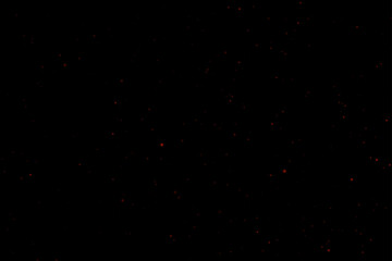 Red dust particles of varying sizes and transparency on a black background. Abstract glowing effect with a festive atmosphere.
