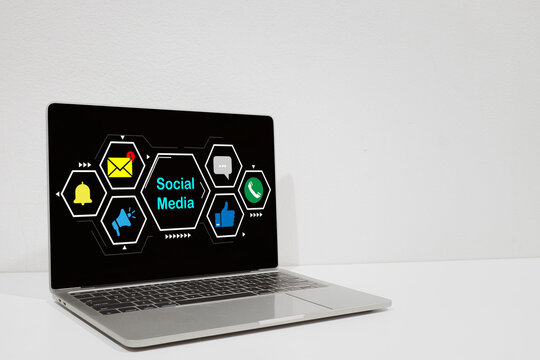 Social media marketing concept. Laptop screen showing social media text and icons like email, chat, and like, representing digital communication, online business strategy, and technology.