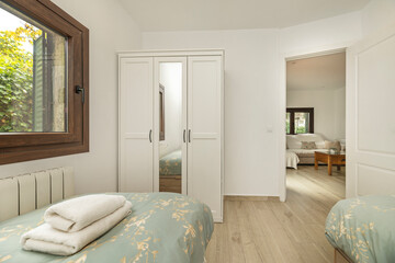 Image of a bed with a light canopy and a satin comforter printed with subtle botanical motifs in shades of green and beige.