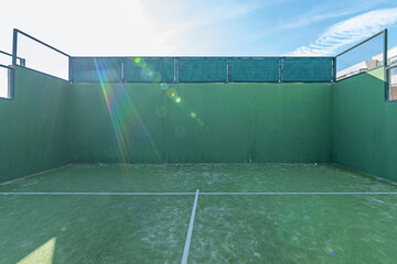 A tennis court with green walls and flooring, a ball rolling and a ray of sunshine slowly entering... a beautiful summer day