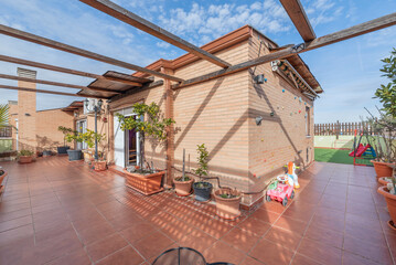 Rooftop terrace with solarium and outdoor dining area, paved with composite wood decking and enclosed with a frameless, transparent glass railing
