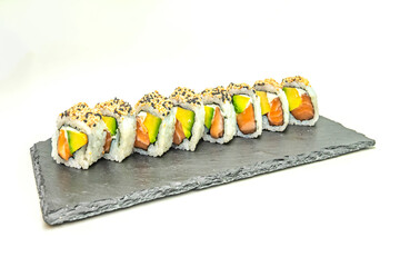 Traditional Japanese uramaki with rice on the outside, nori on the inside, fresh salmon, avocado, and cucumber, garnished with toasted sesame seeds