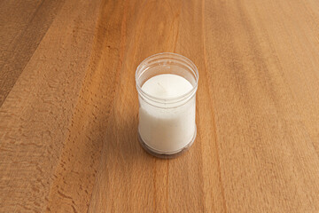 A white candle inside a plastic container