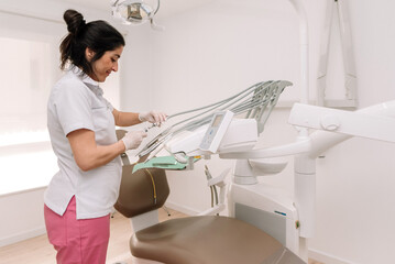 Female Dentist preparing tools for dental checkup in modern clinic